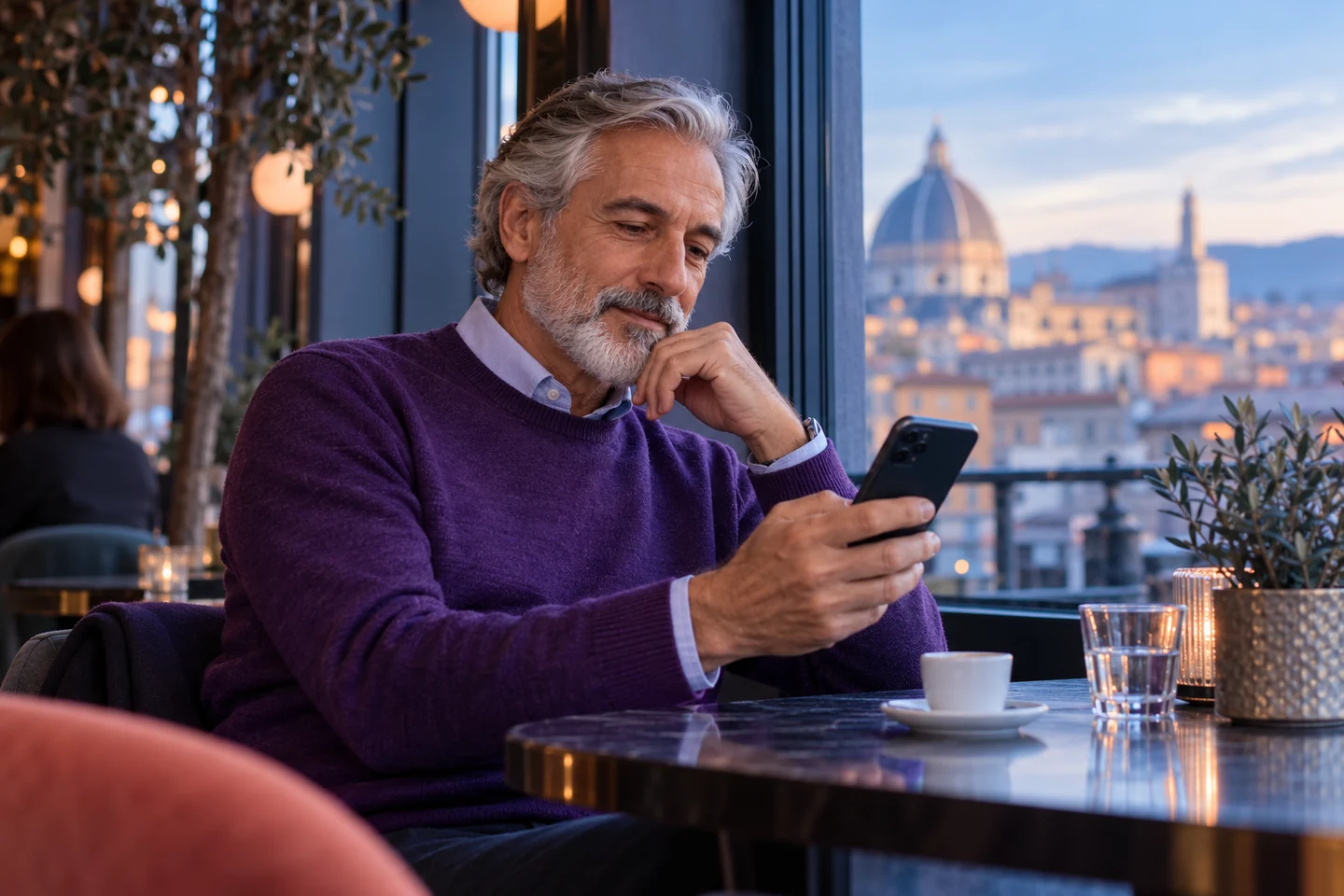 Uomo che confronta telefono e appunti vicino alla finestra di un caffè